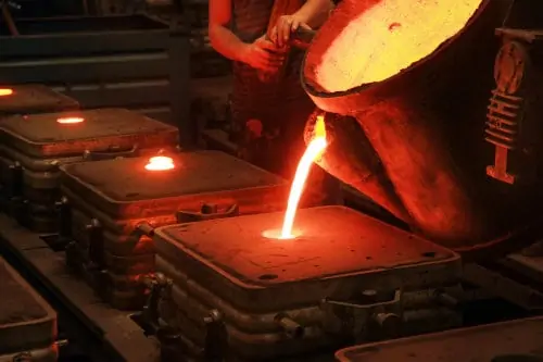 Operator pouring molten metal into a sand cast mold