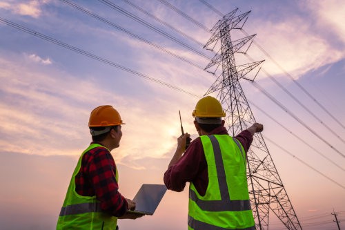 Engineer and worker inspecting high-voltage electrical pole