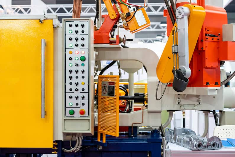 Close up of ladle and mechanical arm of high pressure aluminum die cast machine and control panel