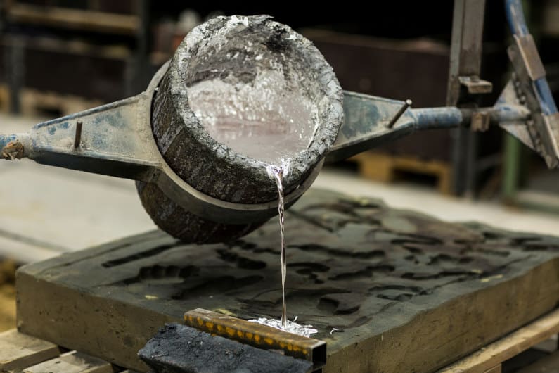 Pouring molten aluminum into a sand cast mold