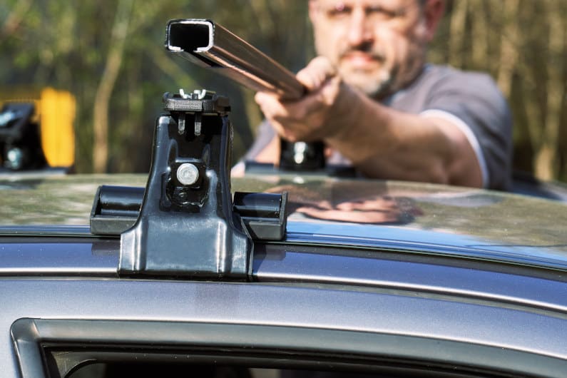 Man installing a car roof rack outdoors 