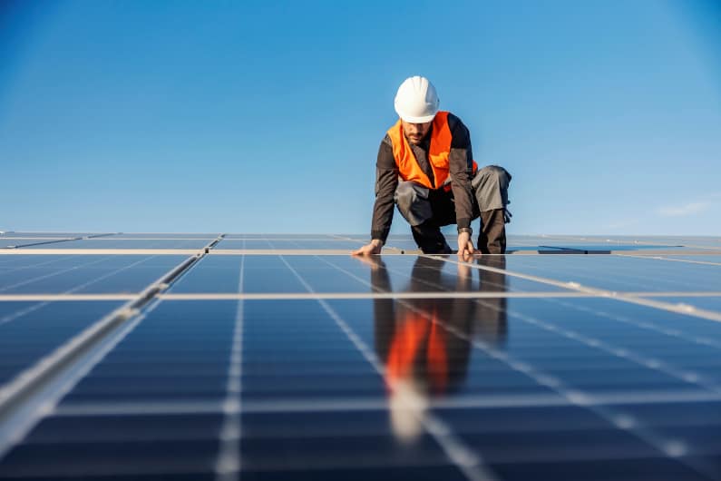 Worker installing solar panels on a rooftop. 