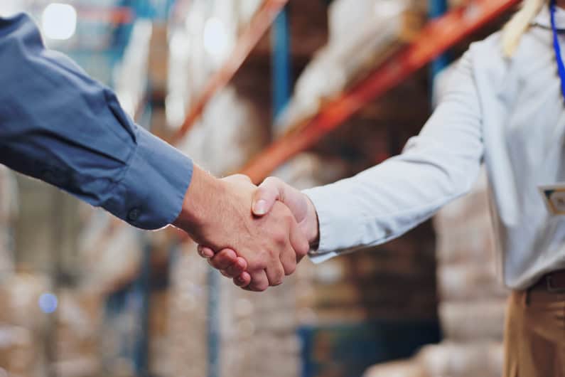 Two people shaking hands inside a warehouse